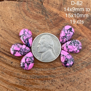 Puede incluir: Seis gemas en forma de lágrima con un vibrante patrón rosa y negro están dispuestas alrededor de una moneda. Las gemas miden 14x9mm a 15x10mm y están etiquetadas como D-82, 19 cts.