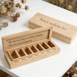 May include: A wooden medicine box with a hinged lid, engraved with "Peter's medicine box." The open box reveals seven compartments labeled for each day of the week. The inside lid has an engraved message.