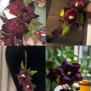 May include: A handcrafted floral hair accessory featuring deep burgundy, star-shaped blossoms with prominent pale yellow centers and green leaves. The design includes thin, dark stems and delicate petals, capturing the appearance of a dark clematis flower.