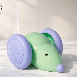 Peut inclure: Une souris jouet verte et violette avec de grandes roues et une queue incurvée. Le jouet a un corps arrondi, un petit nez et des yeux noirs. Les roues sont de couleur violet clair. Le jouet est conçu pour les animaux de compagnie.