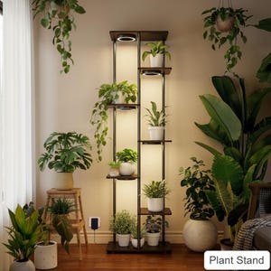 May include: A tall, dark brown plant stand with multiple shelves and built-in lights, displaying various potted plants. The stand is rectangular with a modern design, and the plants are a mix of green foliage. The text "Plant Stand" is visible.