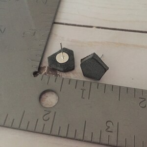 May include: A pair of gray hexagonal stud earrings with silver posts.