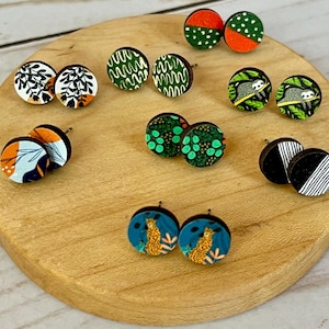 May include: Assortment of colorful wooden earrings with various patterns, including geometric designs, floral motifs, and animal prints. The earrings are displayed on a wooden surface.