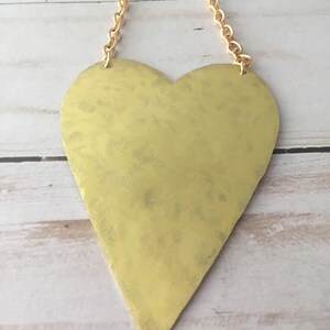 Op de afbeelding: Een gouden hartvormige hanger met een ketting. Het hart is getextureerd en heeft een licht gehammerde afwerking.