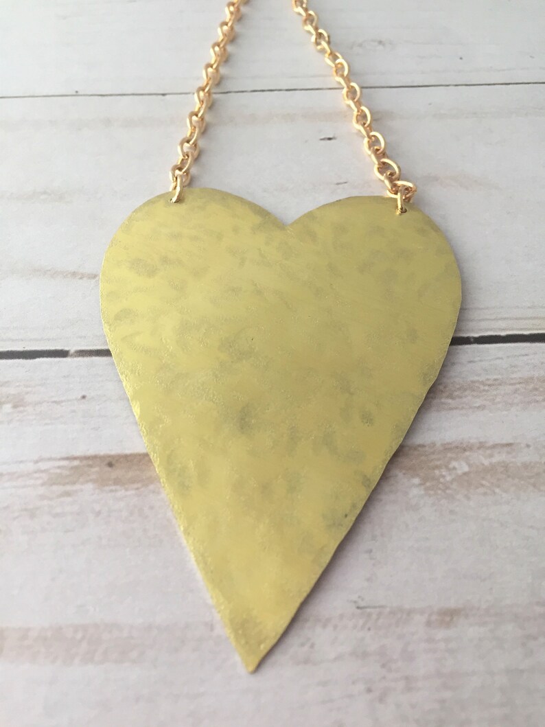 Op de afbeelding: Een gouden hartvormige hanger met een ketting. Het hart is getextureerd en heeft een licht gehammerde afwerking.