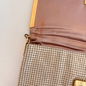 Bone and gold metal mesh handbag opened to reveal pink lining and discoloration.