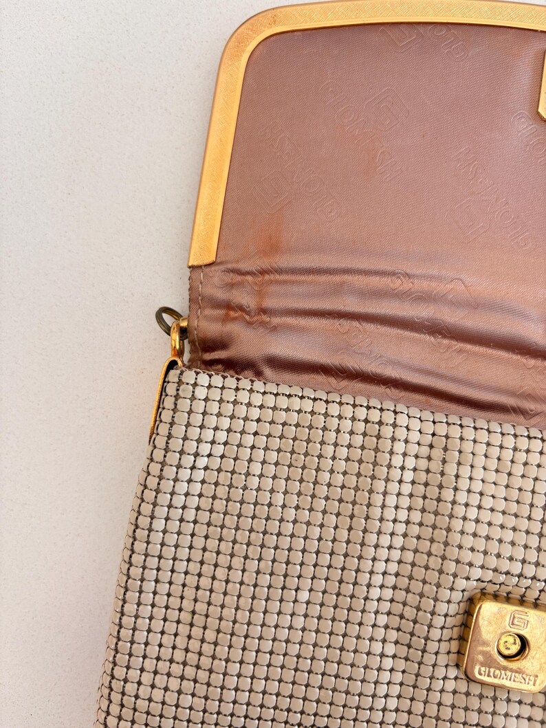 Bone and gold metal mesh handbag opened to reveal pink lining and discoloration.