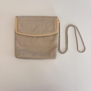 Puede incluir: Un bolso de mano vintage de malla beige con un marco dorado y una correa de cadena plateada. El bolso rectangular tiene una parte superior curvada y un fino patr&oacute;n de rejilla. La cadena es un dise&ntilde;o delicado y enlazado.
