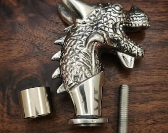 May include: A silver-coloured metal dragon head handle with a textured scale pattern, featuring a smooth cylindrical collar and a separate threaded metal bolt. The dragon head has a prominent horn, open mouth, and sharp details across the surface.
