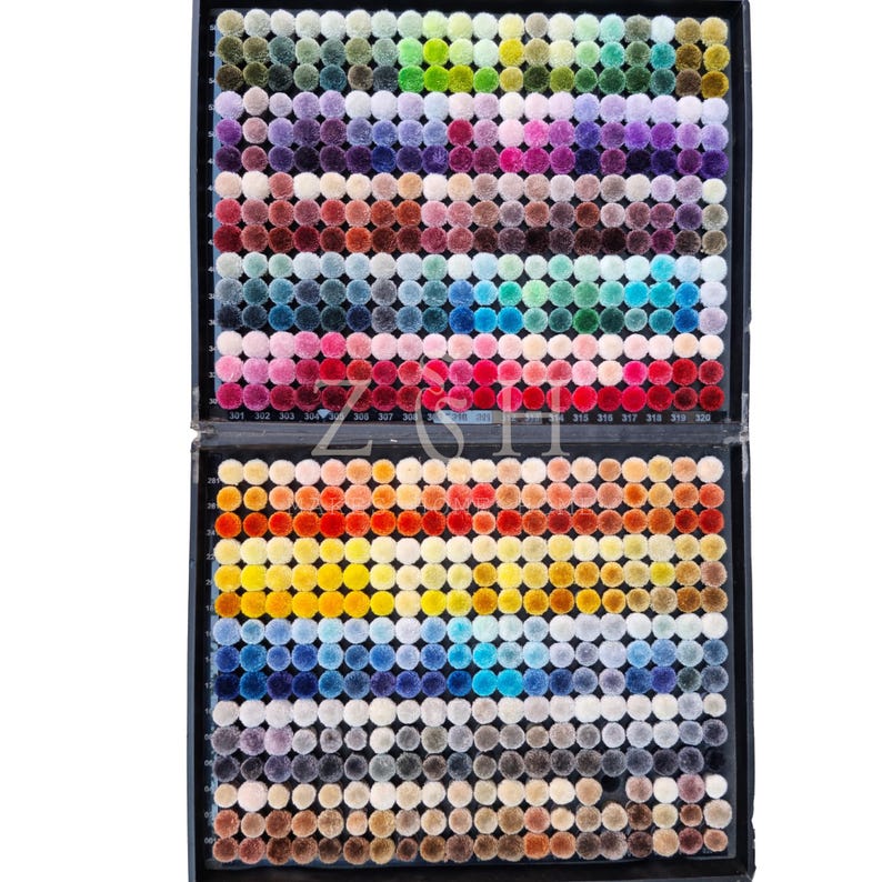 Puede incluir: Un expositor de dos niveles lleno de cientos de peque&ntilde;os pompones de colores. Los pompones est&aacute;n dispuestos en filas y columnas, mostrando un amplio espectro de colores, desde verdes vibrantes y rosas hasta azules oscuros y marrones. El texto "ZSH" es visible.