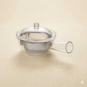 May include: A clear glass teapot featuring a side handle and a removable stainless steel mesh infuser basket. The teapot includes a matching glass lid with a small knob handle, designed for brewing loose leaf tea with a visible infusion process.