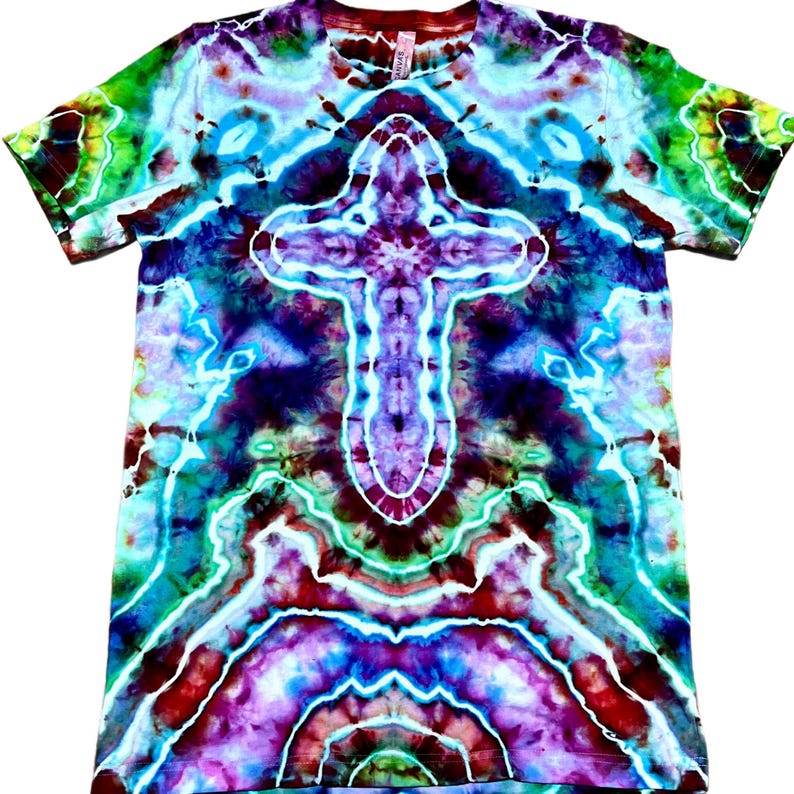 May include: A short-sleeve t-shirt featuring a vibrant tie-dye pattern in shades of purple, blue, teal, and green. The design showcases a prominent, symmetrical cross shape in the center, created with white lines that contrast against the colors.