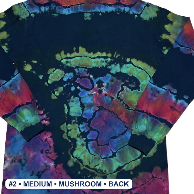 May include: A long-sleeve shirt featuring a dark base with a vibrant tie-dye pattern in shades of green, blue, purple, and red. The design includes a central spiral motif. A white label at the bottom reads #2 &bull; MEDIUM &bull; MUSHROOM &bull; BACK.
