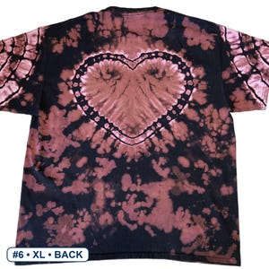 Peut inclure: Un t-shirt noir &agrave; manches courtes avec un motif tie-dye invers&eacute; dans des tons brun-rouge&acirc;tre. Le design pr&eacute;sente une forme de c&oelig;ur bien visible au centre du dos, entour&eacute;e de taches abstraites. Le texte en bas indique #6 &bull; XL &bull; BACK.