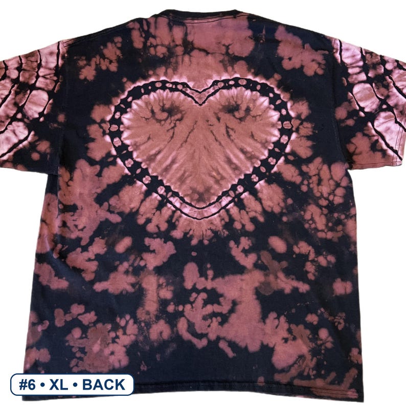 Peut inclure: Un t-shirt noir &agrave; manches courtes avec un motif tie-dye invers&eacute; dans des tons brun-rouge&acirc;tre. Le design pr&eacute;sente une forme de c&oelig;ur bien visible au centre du dos, entour&eacute;e de taches abstraites. Le texte en bas indique #6 &bull; XL &bull; BACK.
