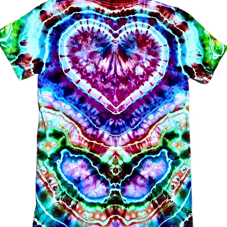 May include: A short-sleeve t-shirt featuring a vibrant tie-dye pattern with a prominent central heart shape. The design incorporates swirling colors of deep purple, magenta, bright turquoise, lime green, and white, creating a complex, symmetrical effect.