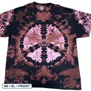 Peut inclure: Un t-shirt &agrave; manches courtes avec un motif tie-dye noir et rose clair et un grand signe de paix centr&eacute; sur la poitrine. Le t-shirt poss&egrave;de une encolure ronde et une petite &eacute;tiquette blanche au col int&eacute;rieur. Le texte indique #6 &bull; XL &bull; FRONT.