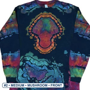 May include: A black long-sleeve shirt featuring a central tie-dye mushroom graphic in shades of orange, green, and blue, with additional tie-dye patterns on the sleeves. The text #2 &bull; MEDIUM &bull; MUSHROOM &bull; FRONT is printed at the bottom.