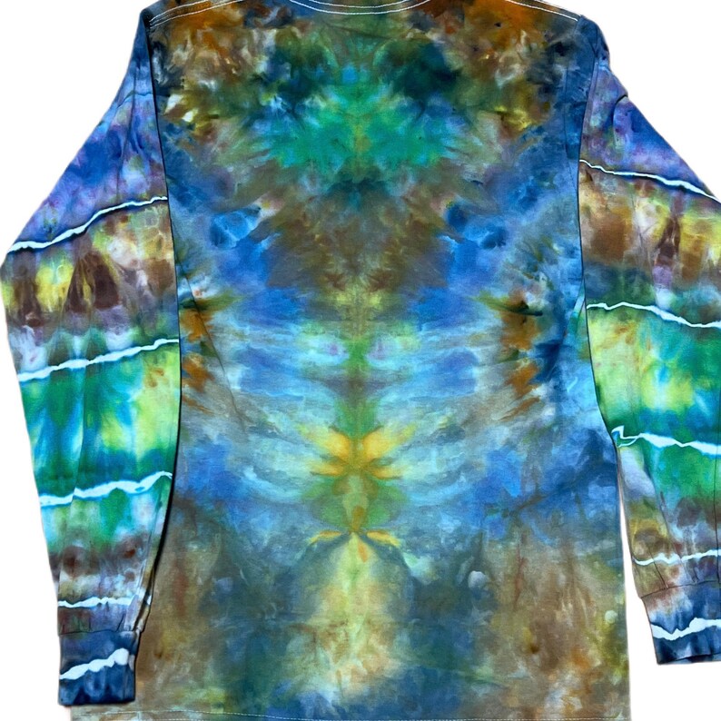 May include: A long-sleeve shirt featuring a tie-dye pattern in shades of blue, green, yellow, and brown. The design displays a symmetrical, fluid colour blend across the torso and sleeves, with distinct white horizontal lines on the sleeves.