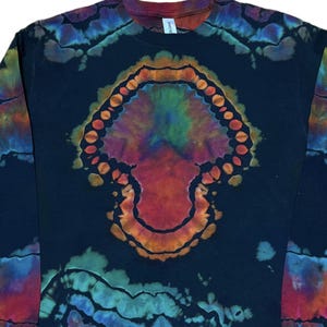 May include: A black long-sleeve shirt featuring a central tie-dye mushroom design in shades of red, orange, green, and purple. The garment has a crew neckline and additional tie-dye patterns in blue, green, and red along the sleeves and lower hem.