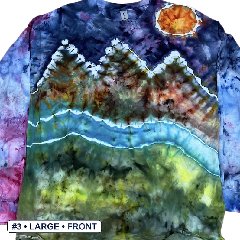 May include: A long-sleeve tie-dye shirt featuring a landscape design with a dark blue night sky, a bright orange sun, mountain peaks, a winding light blue river, and a green grassy foreground. The shirt includes a label reading #3 &bull; LARGE &bull; FRONT.