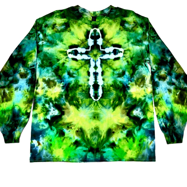 May include: A long-sleeve shirt featuring a tie-dye pattern in shades of lime green, forest green, and dark teal. The center of the shirt displays a prominent white cross shape created through the tie-dye process, set against the vibrant colors.