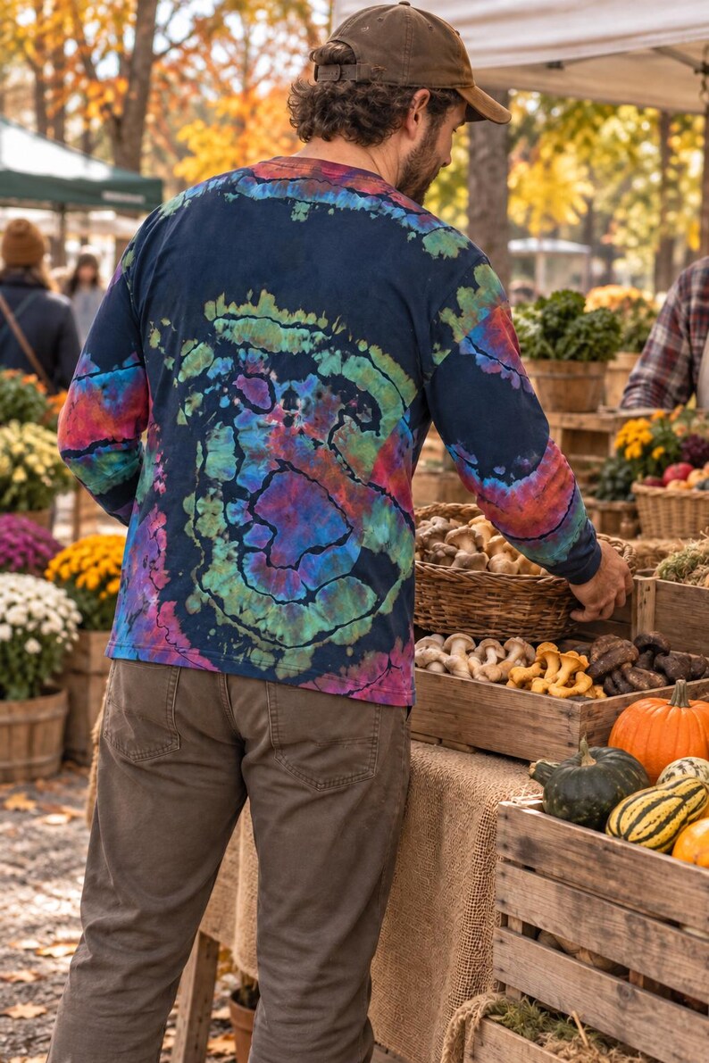 May include: A long-sleeve shirt featuring a dark navy blue base with a vibrant tie-dye spiral pattern in shades of green, purple, and red. The shirt has a crew neckline and long sleeves, showcasing a colorful, swirling design across the back.