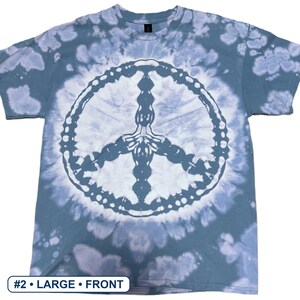 Peut inclure: Un t-shirt &agrave; manches courtes pr&eacute;sentant un motif tie-dye bleu et blanc avec un grand signe de paix blanc au centre. Le t-shirt comporte une petite &eacute;tiquette rectangulaire dans le coin inf&eacute;rieur gauche avec le texte #2 &bull; LARGE &bull; FRONT.