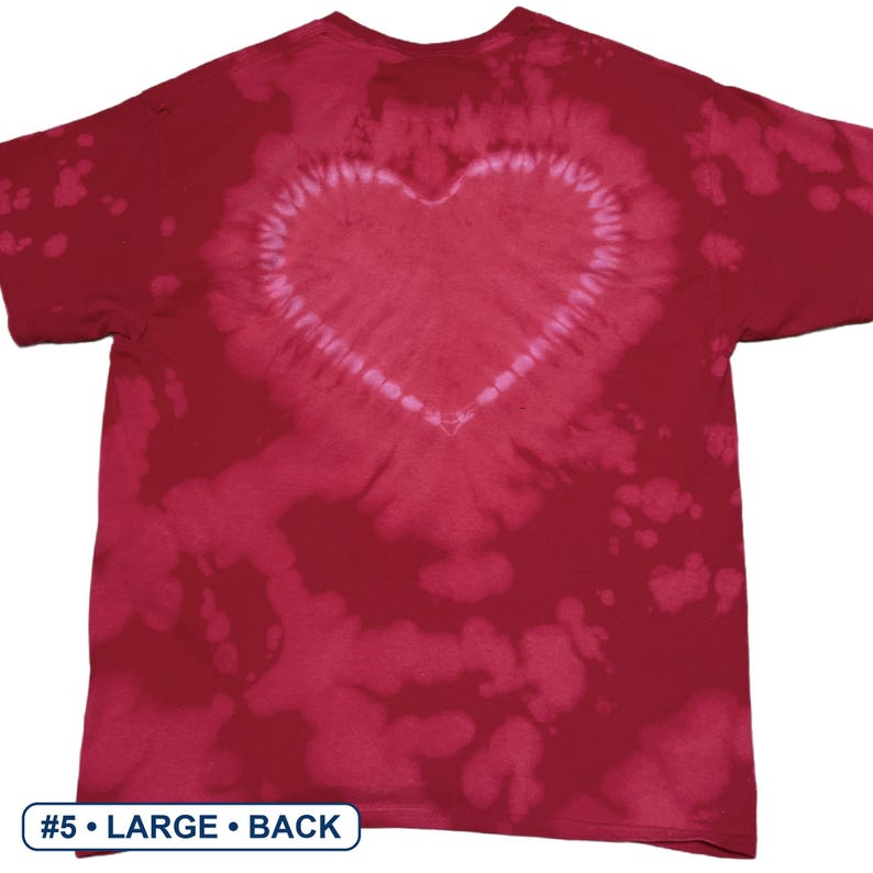 Peut inclure: Un t-shirt &agrave; manches courtes de couleur rouge profond avec un motif tie-dye pr&eacute;sentant une forme de c&oelig;ur rose clair bien visible au dos. Le tissu pr&eacute;sente des taches d&eacute;color&eacute;es irr&eacute;guli&egrave;res. Une &eacute;tiquette en bas indique #5 &bull; LARGE &bull; BACK.