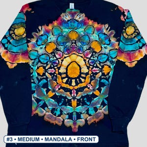 May include: A black long-sleeve shirt featuring a vibrant, symmetrical tie-dye mandala pattern in shades of bright yellow, turquoise, and magenta. The design is centered on the chest and extends onto the sleeves. Text at the bottom reads #3 MEDIUM MANDALA FRONT.