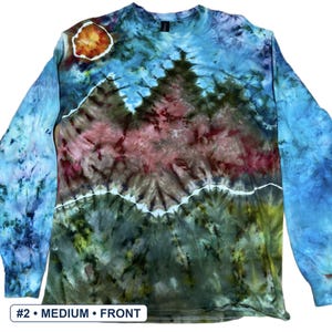 May include: A long-sleeve tie-dye shirt featuring a landscape design with a blue sky, a bright orange sun, and dark green and maroon mountain peaks. The shirt has a crew neckline and includes a white label at the bottom reading #2 &bull; MEDIUM &bull; FRONT.