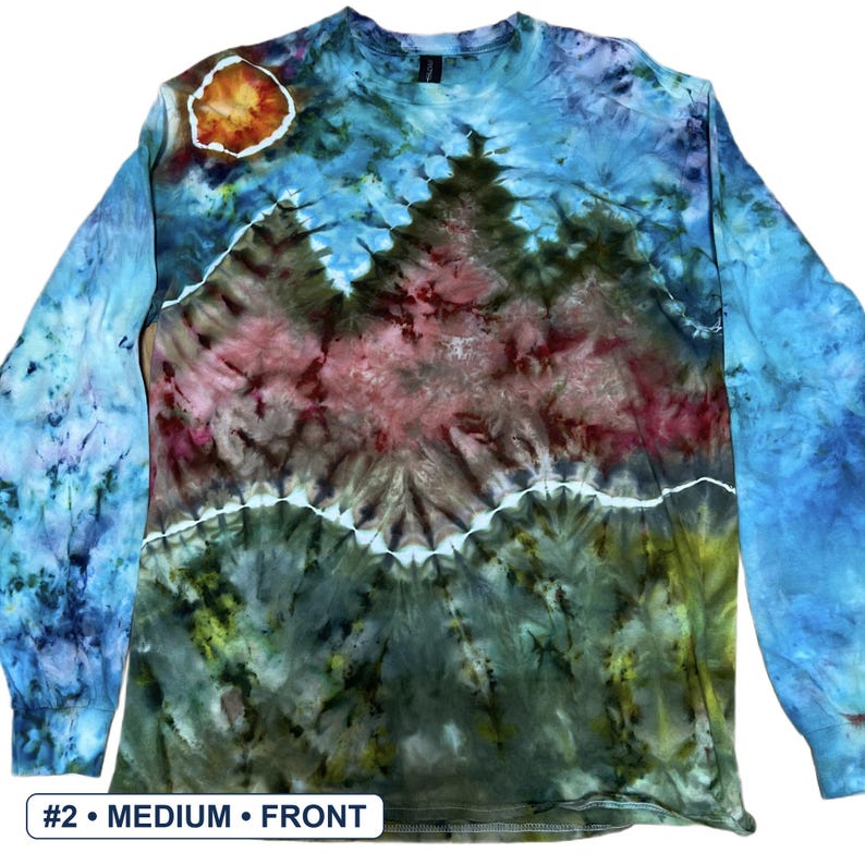 May include: A long-sleeve tie-dye shirt featuring a landscape design with a blue sky, a bright orange sun, and dark green and maroon mountain peaks. The shirt has a crew neckline and includes a white label at the bottom reading #2 &bull; MEDIUM &bull; FRONT.