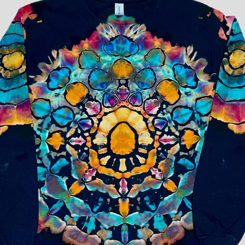 May include: A long-sleeve shirt featuring a black base with a vibrant, symmetrical tie-dye pattern centered on the chest. The design consists of intricate, repeating geometric shapes in shades of bright yellow, orange, turquoise, and magenta.