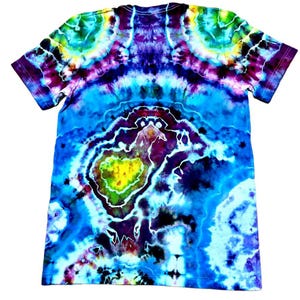 May include: A vibrant tie-dye t-shirt in shades of blue, purple, green, and yellow. The shirt features a unique pattern with a central design resembling a geological formation. The short-sleeved tee is made of soft fabric.