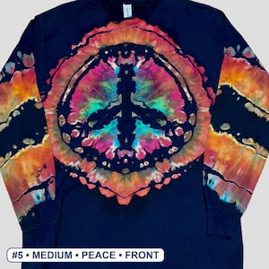 May include: A black long-sleeve shirt featuring a large, central tie-dye peace sign graphic in vibrant shades of pink, orange, and teal. The sleeves also display matching tie-dye patterns. The text #5 &bull; MEDIUM &bull; PEACE &bull; FRONT is visible.