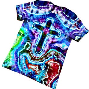 May include: A tie-dye t-shirt with a white cross design. The shirt displays a swirling pattern of blues, purples, greens, and reds. The short-sleeved tee is made of soft fabric.