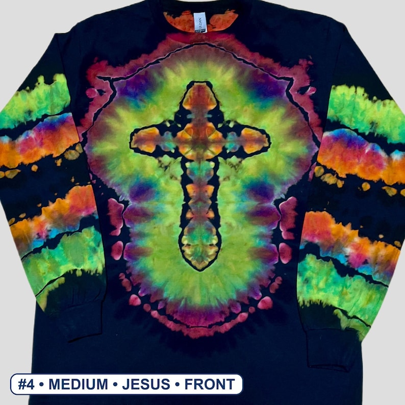 May include: A black long-sleeve shirt featuring a central tie-dye cross design in vibrant shades of green, yellow, orange, and purple. The sleeves display horizontal tie-dye stripes in matching colours. The text #4 &bull; MEDIUM &bull; JESUS &bull; FRONT is visible.