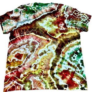 May include: A tie-dye t-shirt with a vibrant, swirling pattern. The colors include shades of red, green, yellow, and brown, with white accents creating a marbled effect. The shirt has a classic crew neck and short sleeves.