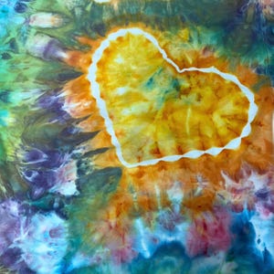May include: A tie-dye fabric featuring a prominent central heart shape outlined in white. The heart is filled with vibrant shades of yellow and orange, while the surrounding area displays a swirling pattern of green, blue, purple, and pink hues.