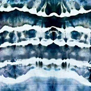 May include: Abstract tie-dye pattern in shades of blue, white, and teal. The design features horizontal bands of color with a textured, watercolor-like effect. The overall aesthetic is reminiscent of a cloudy sky or ocean waves.