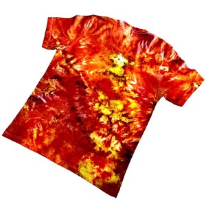 May include: A short-sleeved t-shirt with a vibrant tie-dye pattern in shades of red, orange, and yellow. The shirt's design features a swirling, abstract pattern, creating a unique and eye-catching look. The shirt is made of a soft material.