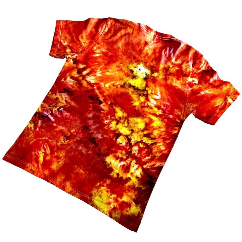 May include: A short-sleeved t-shirt with a vibrant tie-dye pattern in shades of red, orange, and yellow. The shirt's design features a swirling, abstract pattern, creating a unique and eye-catching look. The shirt is made of a soft material.