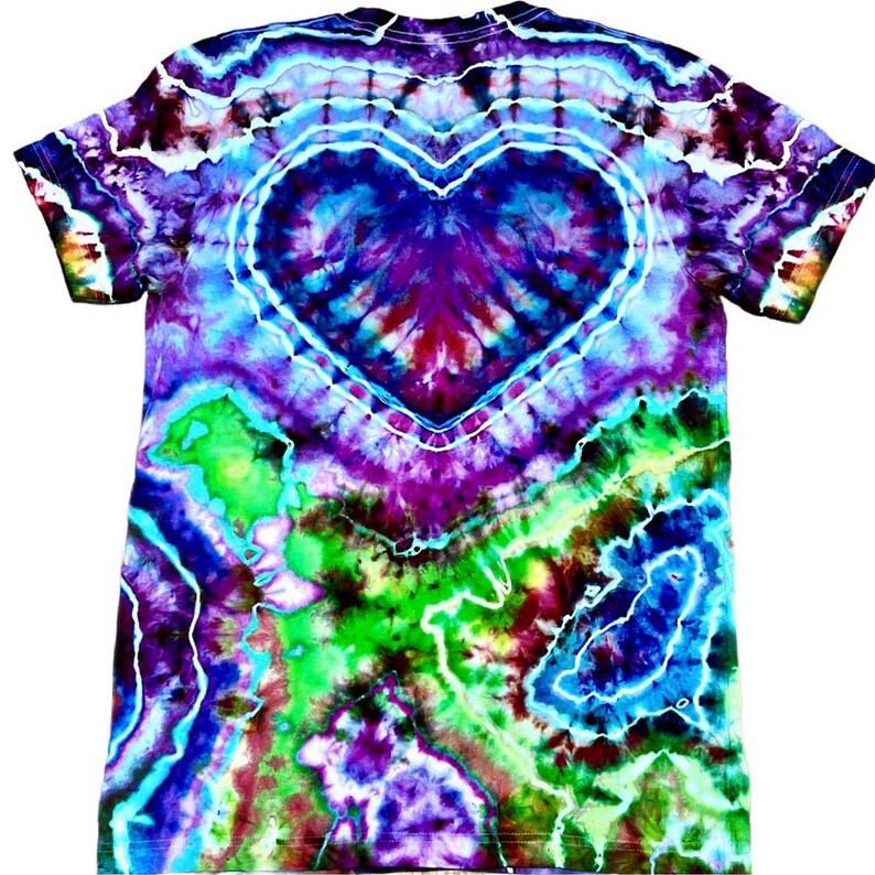 May include: A colourful tie-dye t-shirt with a heart design. The shirt displays a vibrant mix of colours, including blue, purple, green, and red. The heart is outlined in white, and the tie-dye pattern radiates outwards from the centre.