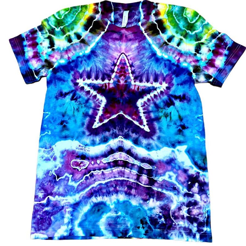 May include: A tie-dye t-shirt with a large white star in the center. The shirt features a vibrant blend of colors, including blue, purple, green, and yellow. The tie-dye pattern creates a swirling effect across the fabric.