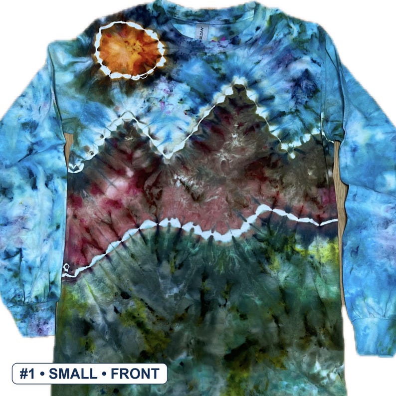May include: A long-sleeve tie-dye shirt featuring a mountain landscape design. The upper section is light blue with a circular orange sun. The middle section shows brown and red mountain peaks, while the lower section is dark green and brown.