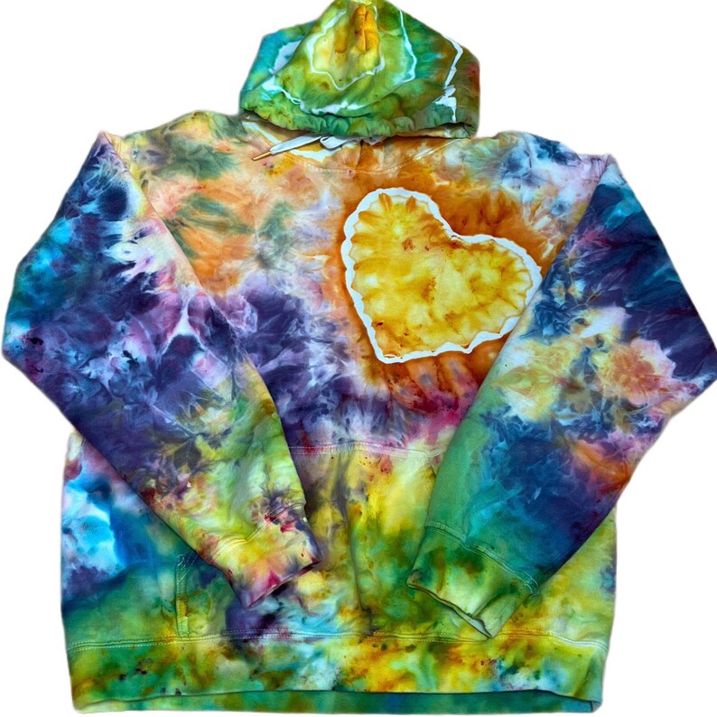 May include: A long-sleeve hooded sweatshirt featuring a vibrant tie-dye pattern in shades of yellow, orange, purple, blue, and green. A prominent yellow heart-shaped patch with a white border is centered on the chest area of the garment.
