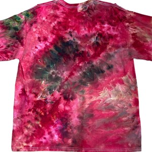Może przedstawiać: Koszulka z kr&oacute;tkim rękawem z żywym wzorem tie-dye w odcieniach głębokiego magenty, jasnego r&oacute;żu i ciemnej szarości antracytowej. Tkanina wykazuje wirujący, marmurkowy efekt z wymieszanymi kolorami na całej przedniej części odzieży.