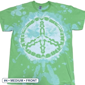 Peut inclure: Un t-shirt &agrave; manches courtes et col rond avec un motif tie-dye dans des tons vert citron et blanc. Le centre du t-shirt pr&eacute;sente un grand signe de paix circulaire blanc. Le texte #4 &bull; MEDIUM &bull; FRONT est visible en bas &agrave; gauche.