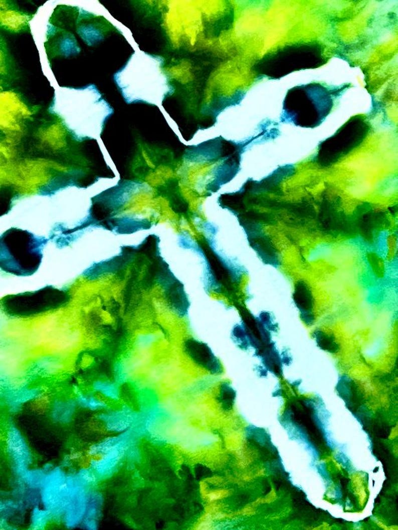 May include: A tie-dye fabric featuring a prominent white cross shape centered against a vibrant background of blended lime green, emerald green, and deep forest green hues. The design displays soft, blurred edges where the colors bleed together.