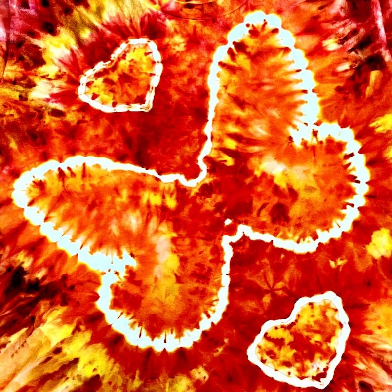 May include: A tie-dye textile in red, orange, and yellow, with three white-outlined heart shapes. The fabric has a swirling pattern, creating a vibrant and artistic design. The overall effect is a colourful and eye-catching piece.